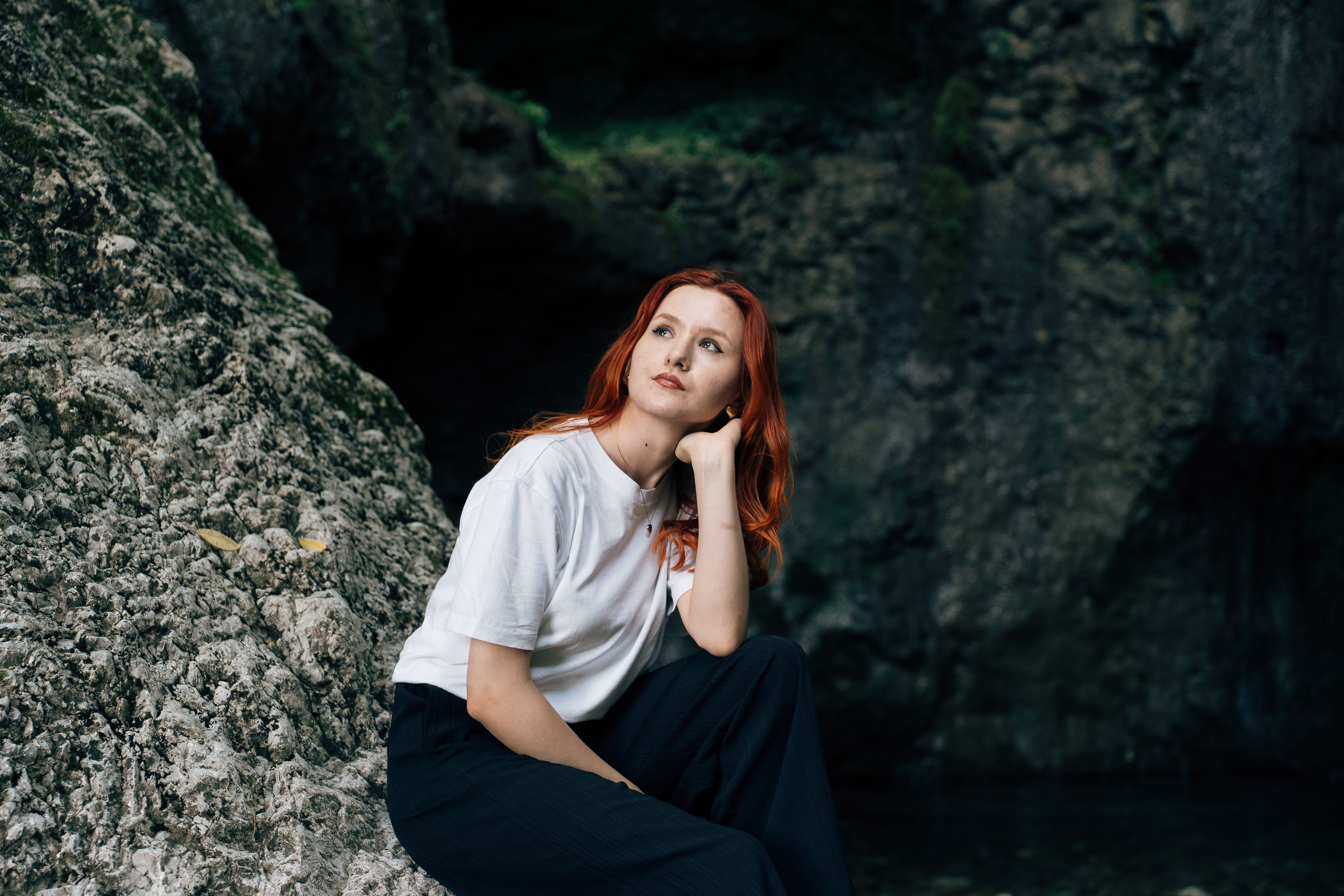 A woman with red hair sitting on a rock · Free Stock Photo