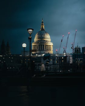 A cinematic view of St. Paul's Cathedral in London illuminated at dusk, blending architecture and city life.
