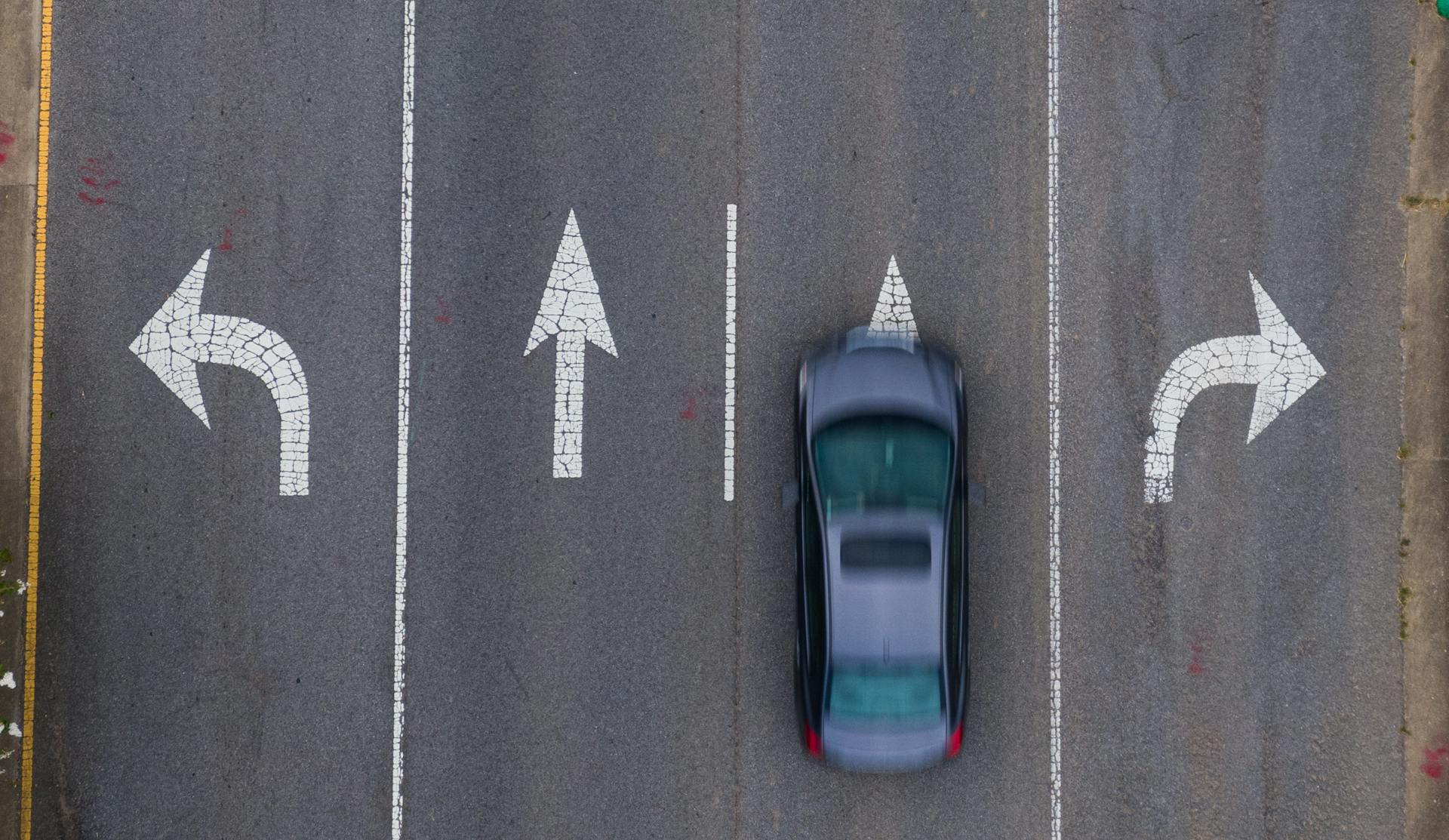 Top-down view of a moving car on a road with directional arrows, emphasizing urban transportation.