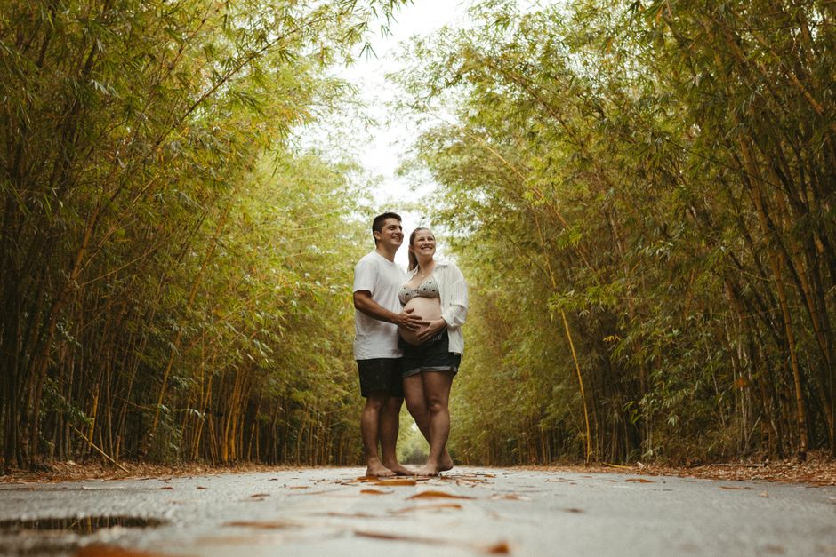 Casal grávido se abraçando em caminho tranquilo