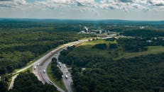 探索高速公路穿越郁郁葱葱林地的壮丽鸟瞰图，捕捉自然与旅行的精髓