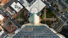 从高处俯瞰，一座现代摩天大楼被城市街道和郁郁葱葱的绿植环绕