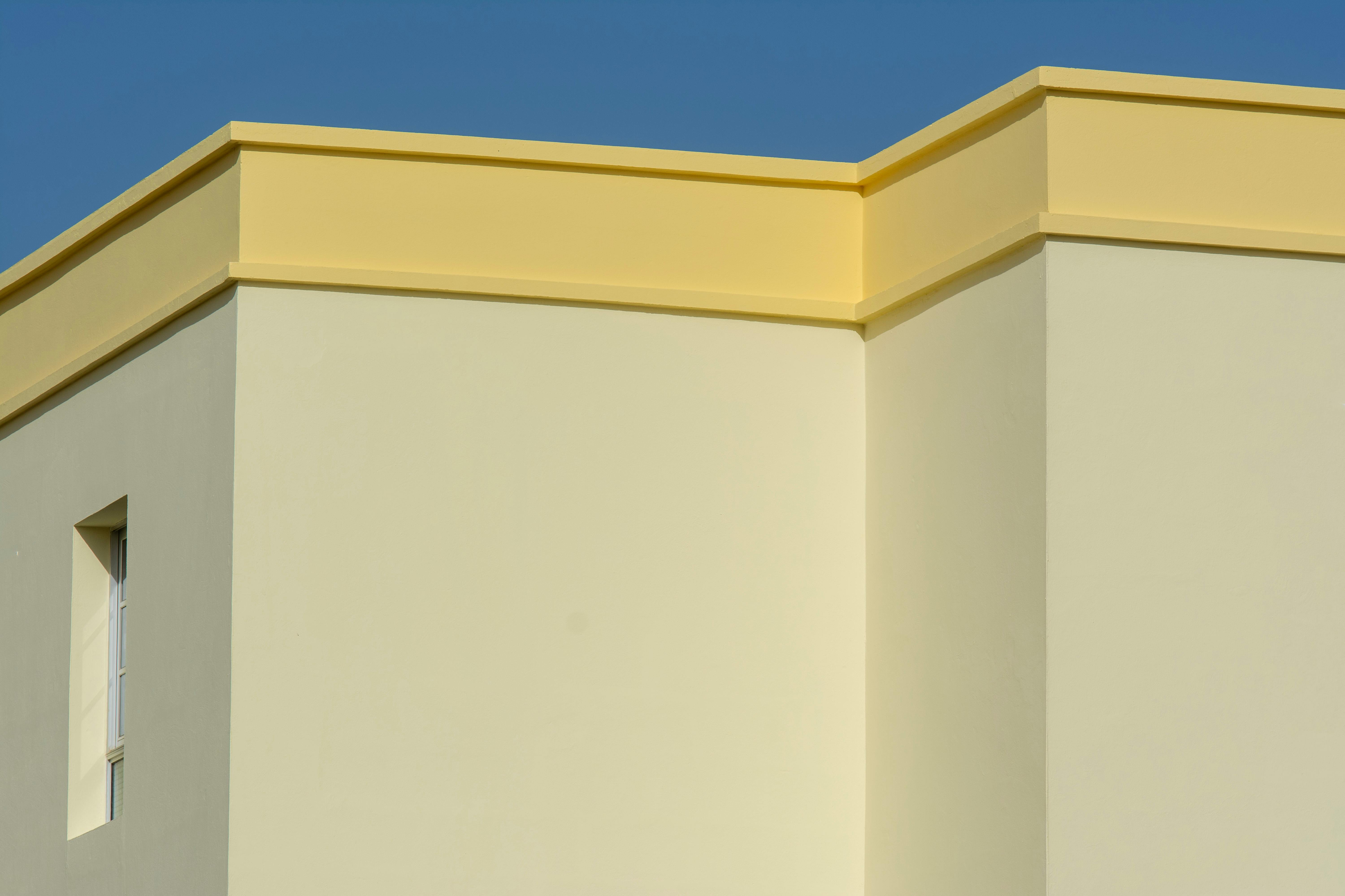 Free A minimalist yellow and beige building facade in bright daylight showcasing clean geometric lines. Stock Photo