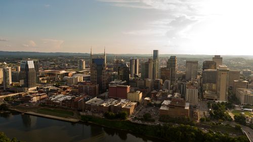 Free Drone shot capturing the modern skyline of Nashville, Tennessee with clear skies and a vibrant cityscape. Stock Photo
