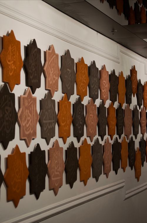 Free Elegant wall of geometric Islamic calligraphy plaques in warm tones. Stock Photo