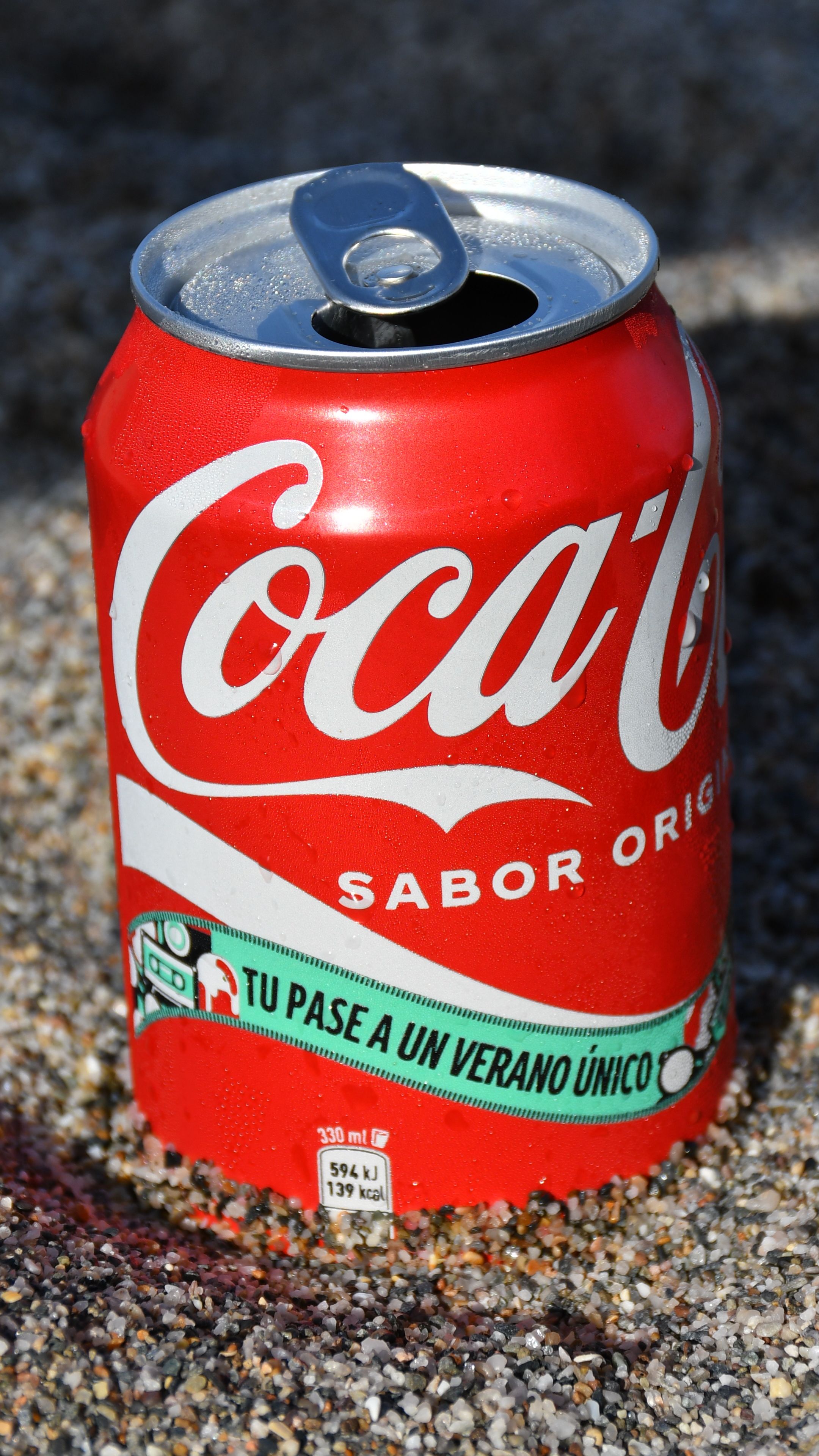 Close-up of a Coca-Cola can outdoors, perfect for summer vibes.