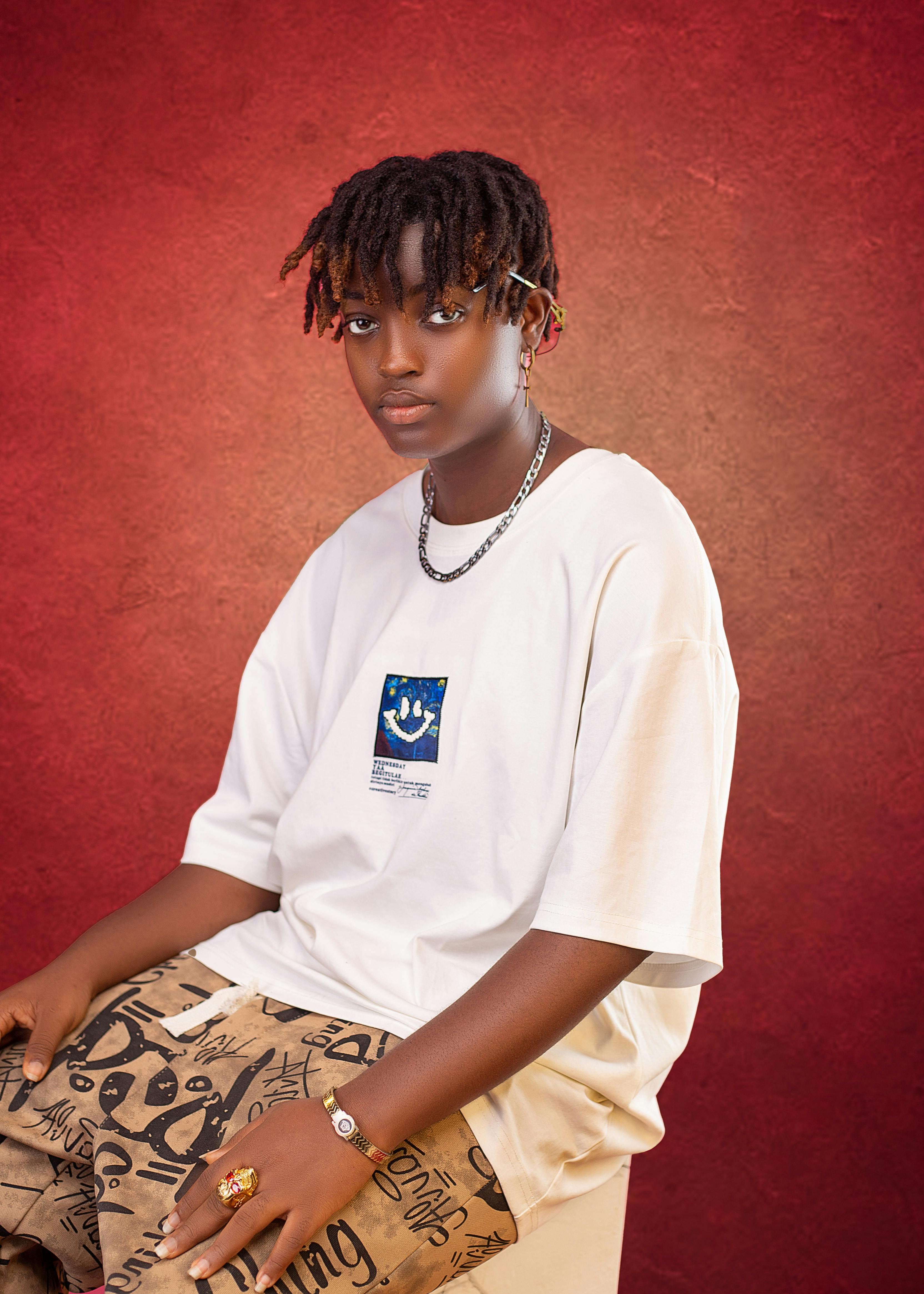 Stylish young man with dreadlocks posing in a studio, dressed in casual oversized t-shirt and graphic pants.