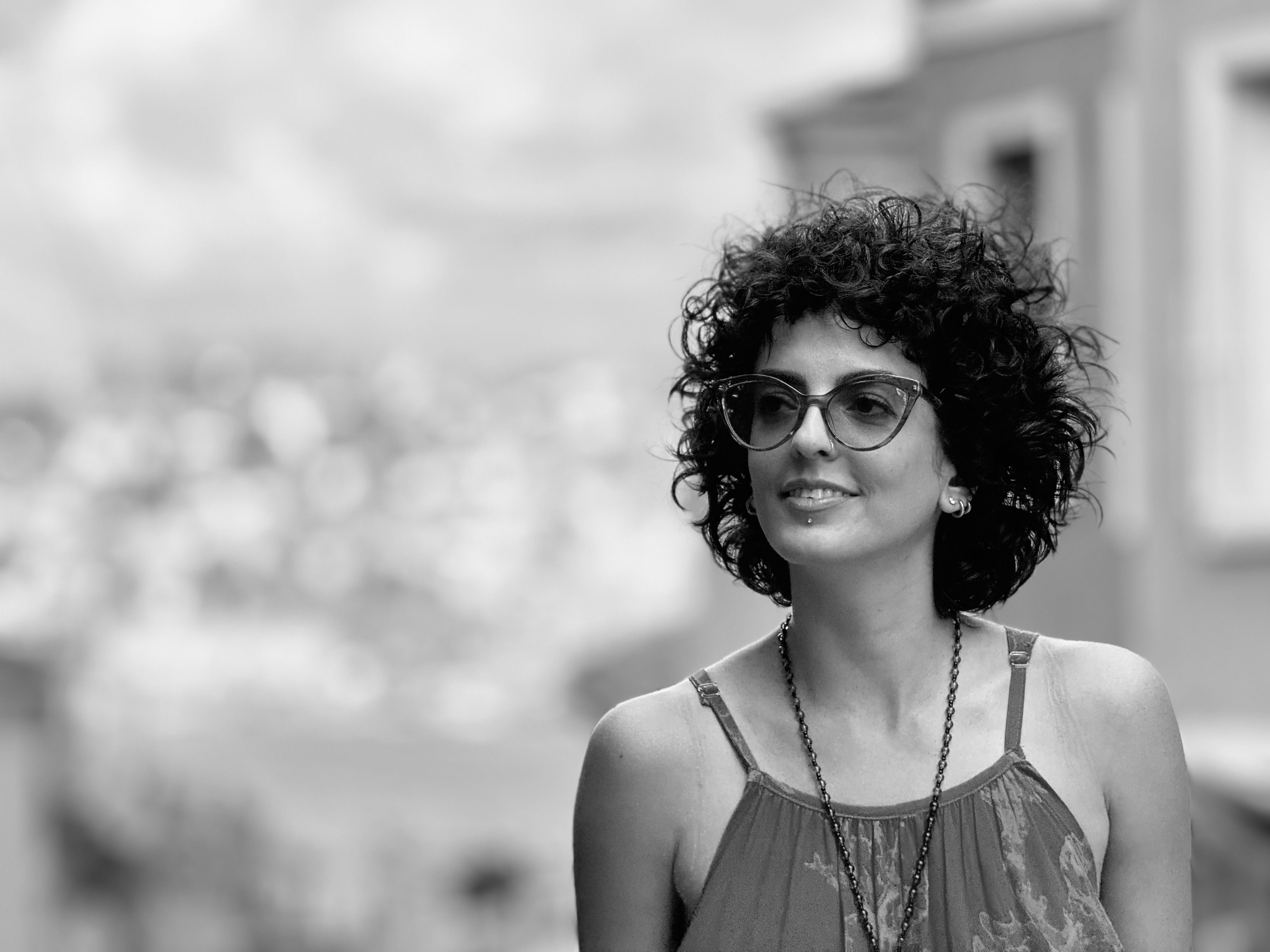 Outdoor portrait of a stylish woman with curly hair and glasses in Fatih, Istanbul, Turkey.