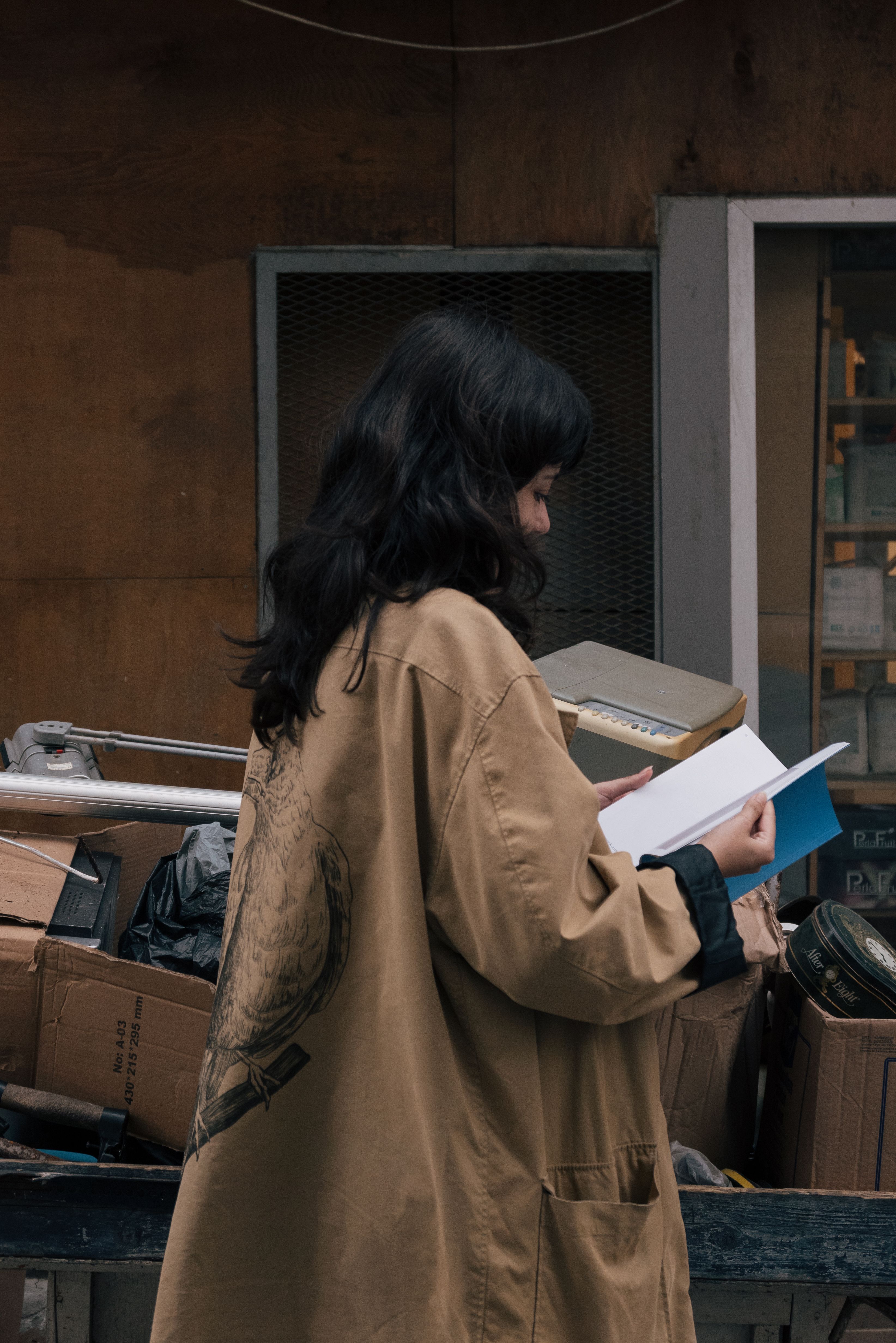 A woman in a trench coat reading a book · Free Stock Photo