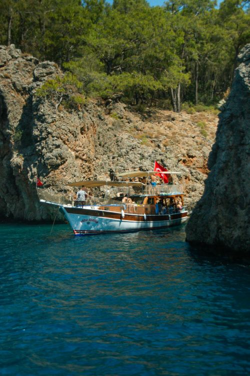 Free A traditional Turkish boat anchored between rocks on a sunny seashore. Stock Photo