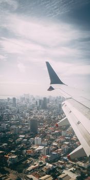 Cityscape from airplane window with skyline in the distance, urban aerial perspective.