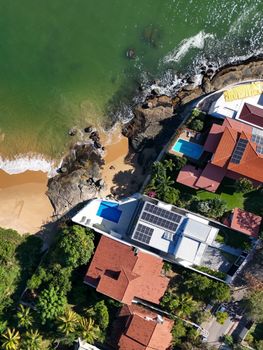 A stunning aerial shot of coastal houses with red rooftops and lush greenery by the sea.