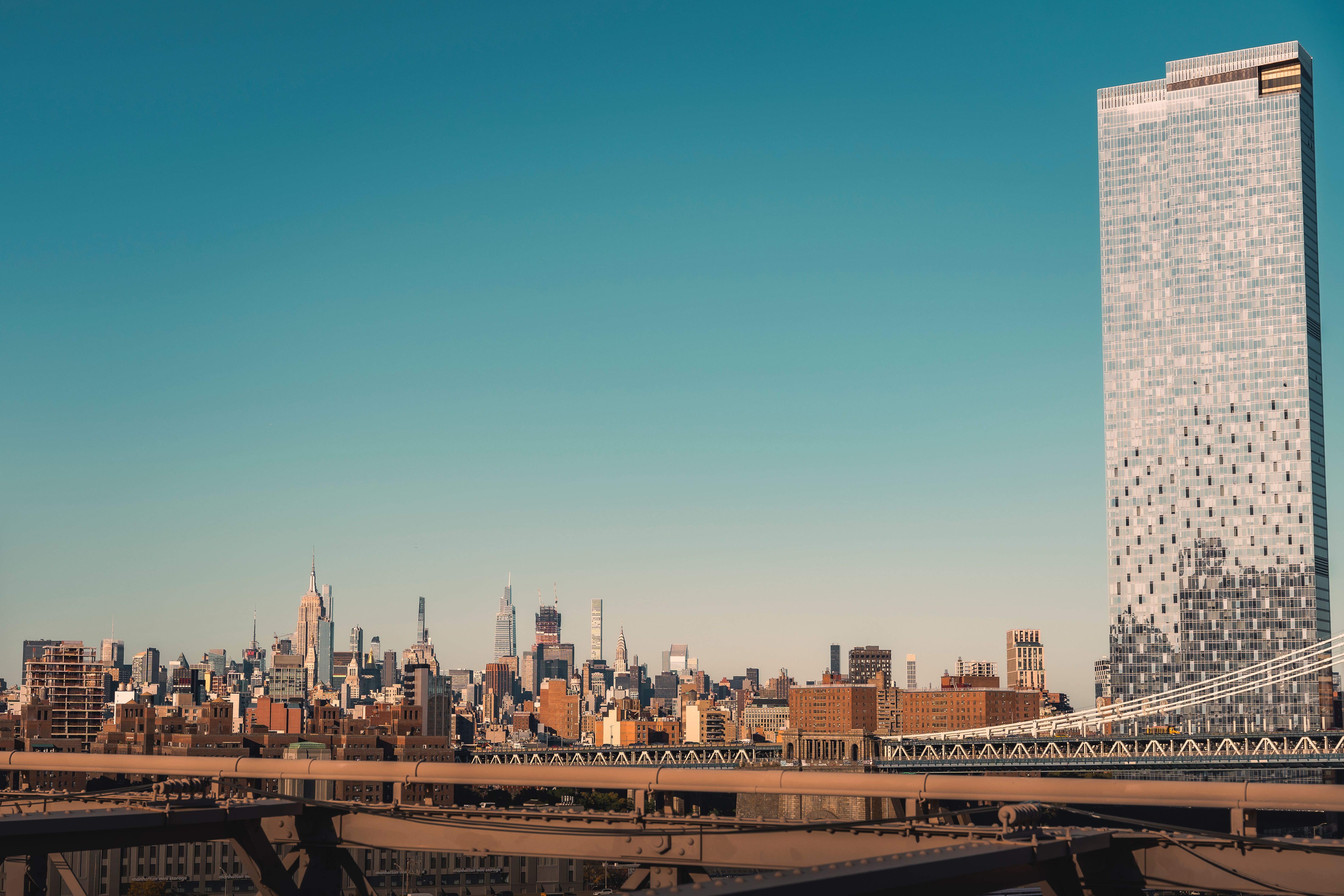 Panoramic view of New York City skyline and bridge under a clear sky.