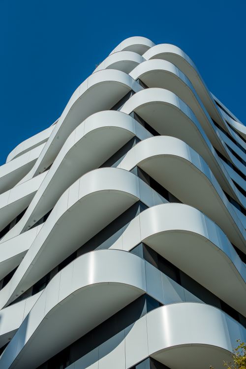 Free Low angle view of a modern residential building with unique curved design under a clear blue sky. Stock Photo