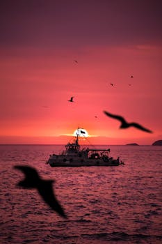 A stunning sunset view in Ancón, Peru with a silhouetted warship and birds over the ocean.