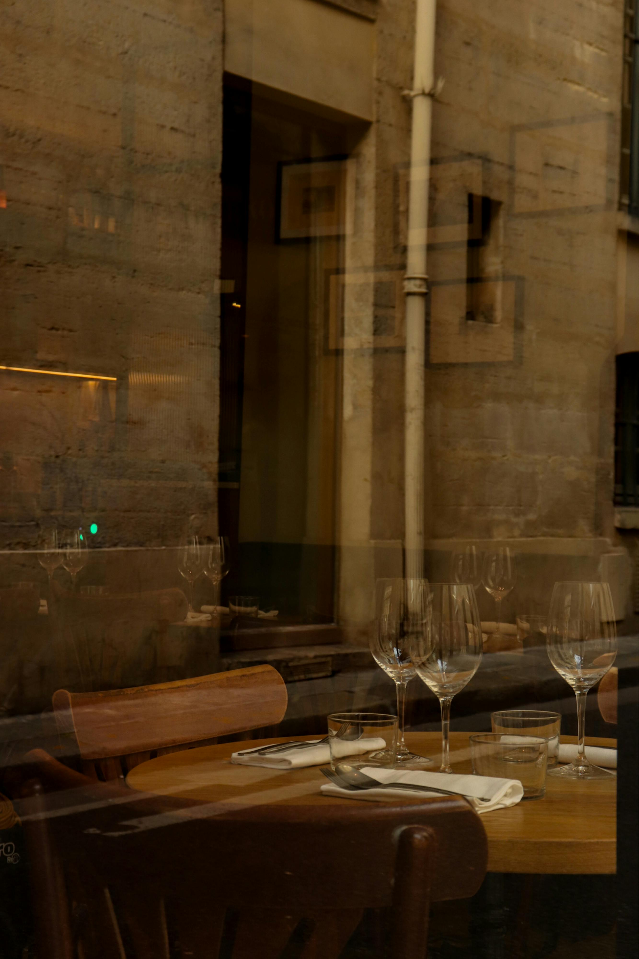 Elegant Parisian cafe interior with table set and reflections on glass window, creating a cozy mood.