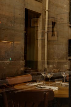 Elegant Parisian cafe interior with table set and reflections on glass window, creating a cozy mood.