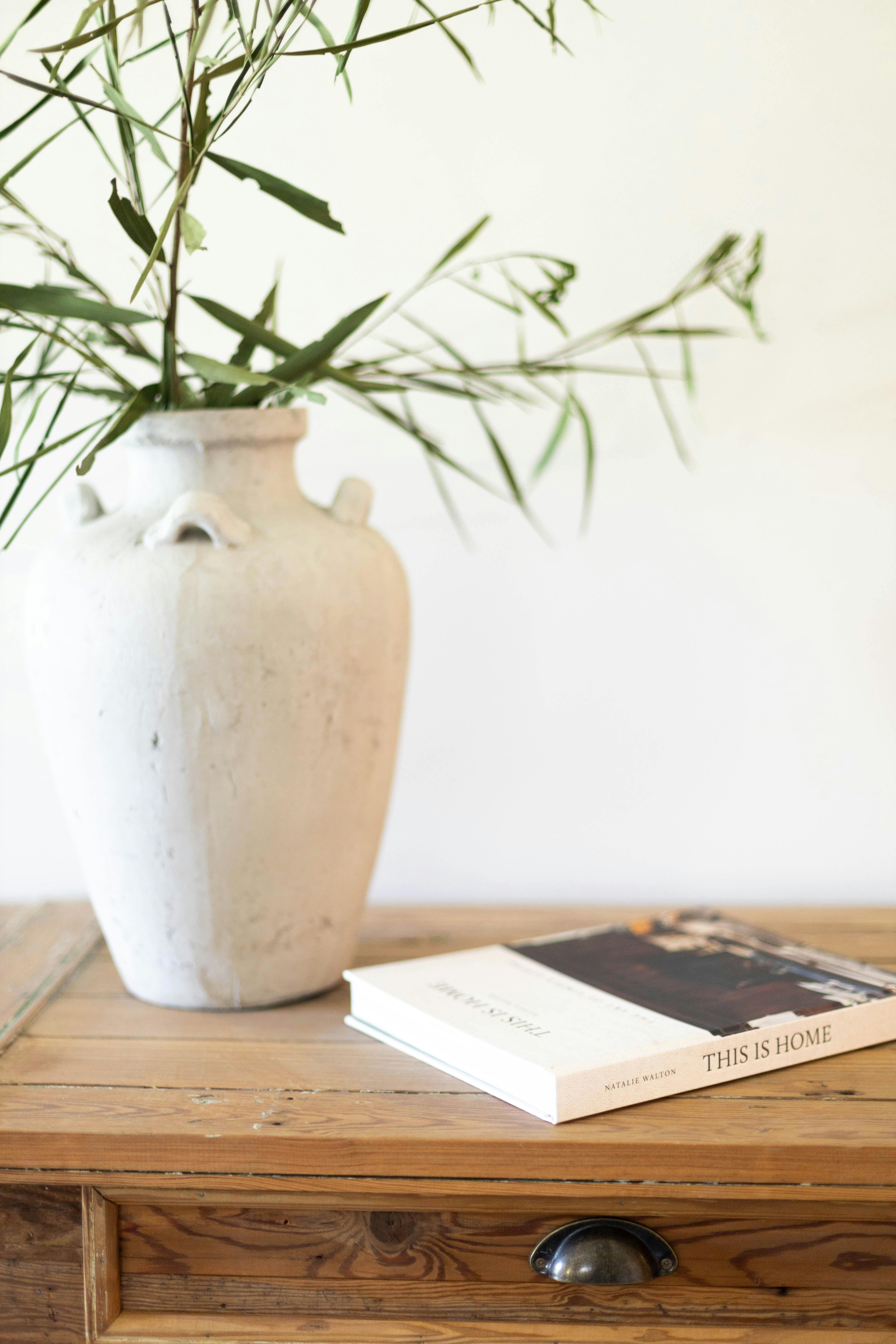 A minimalist setup with a rustic vase and a book on a wooden table for interior design inspiration.