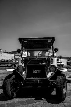 Classic vintage car parked outdoors captured in striking black and white, showcasing its unique retro design.