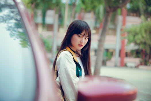 一位穿着休闲服的年轻女子在停放的汽车旁摆姿势，在户外唤起一种宁静而沉思的心情