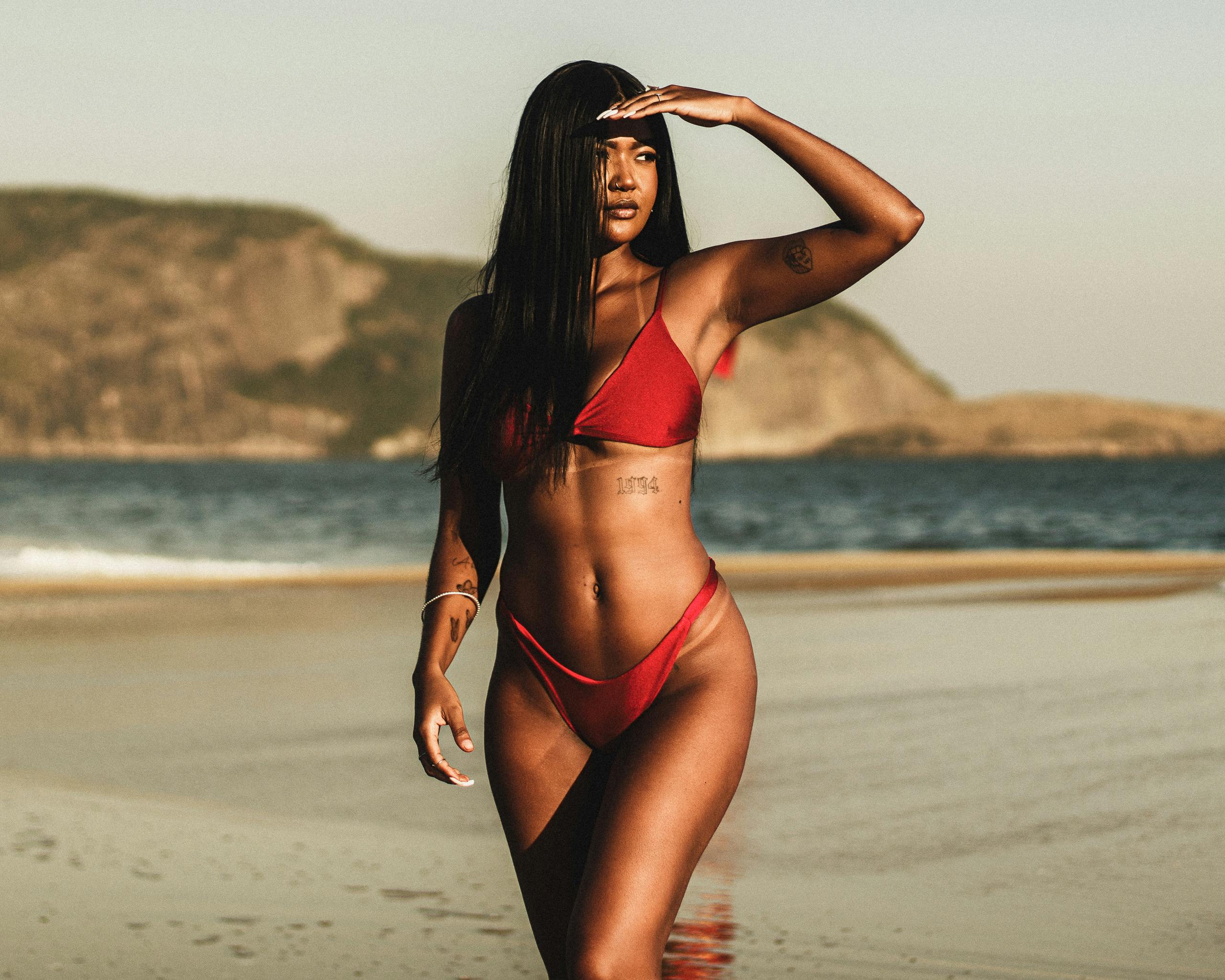 a woman in a red bikini standing on the beach