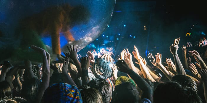 Lively concert scene with excited crowd and performer in a transparent ball at night.