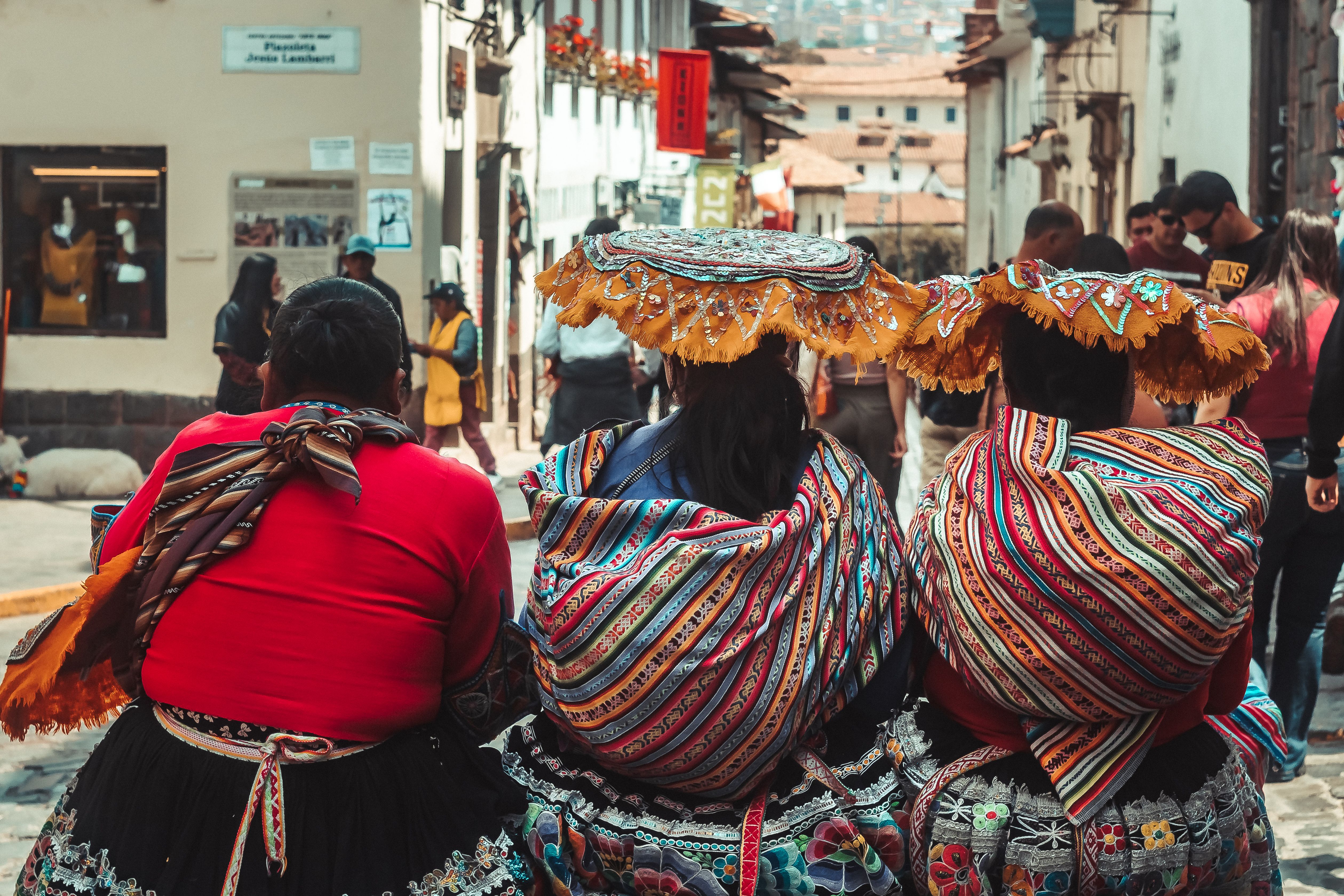 Women in vibrant traditional dresses in the streets of Cusco, Peru, showcasing cultural heritage.