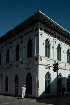 A classic white building with arched windows, captured in bright sunlight on a city street corner.