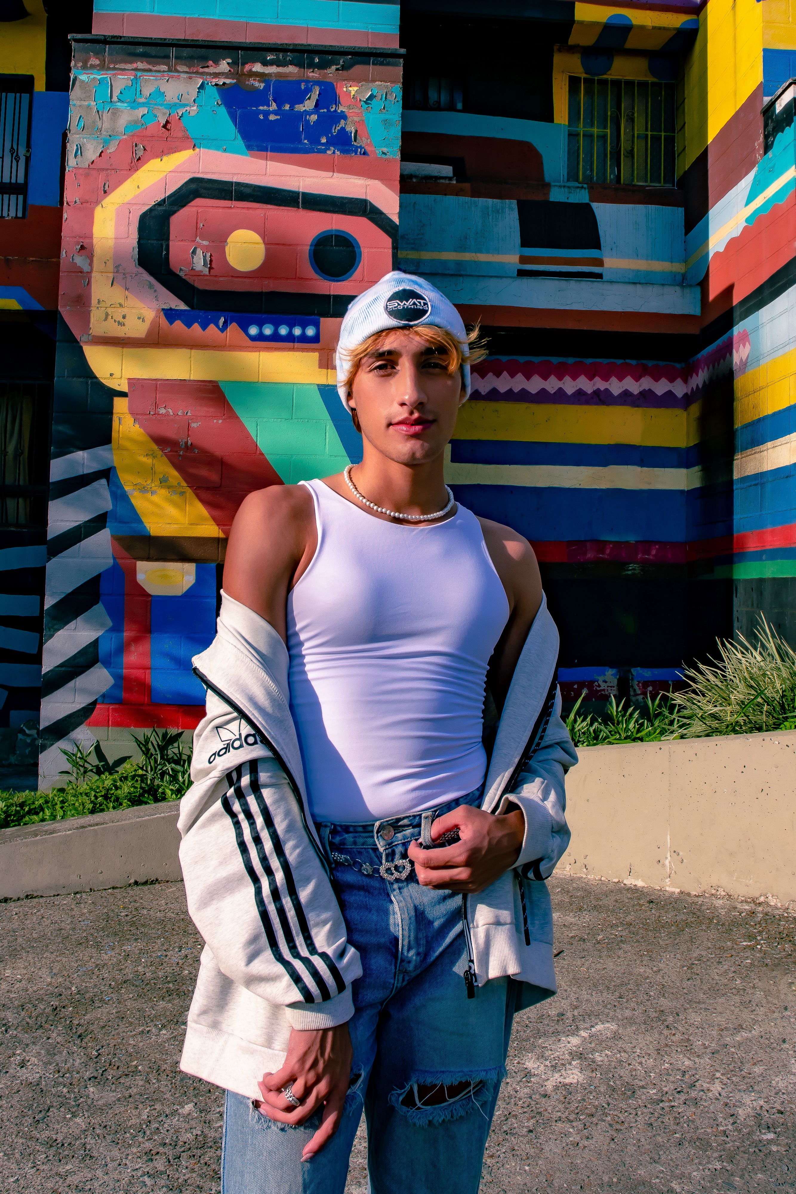 Stylish individual poses against colorful street art in Medellín, Colombia.
