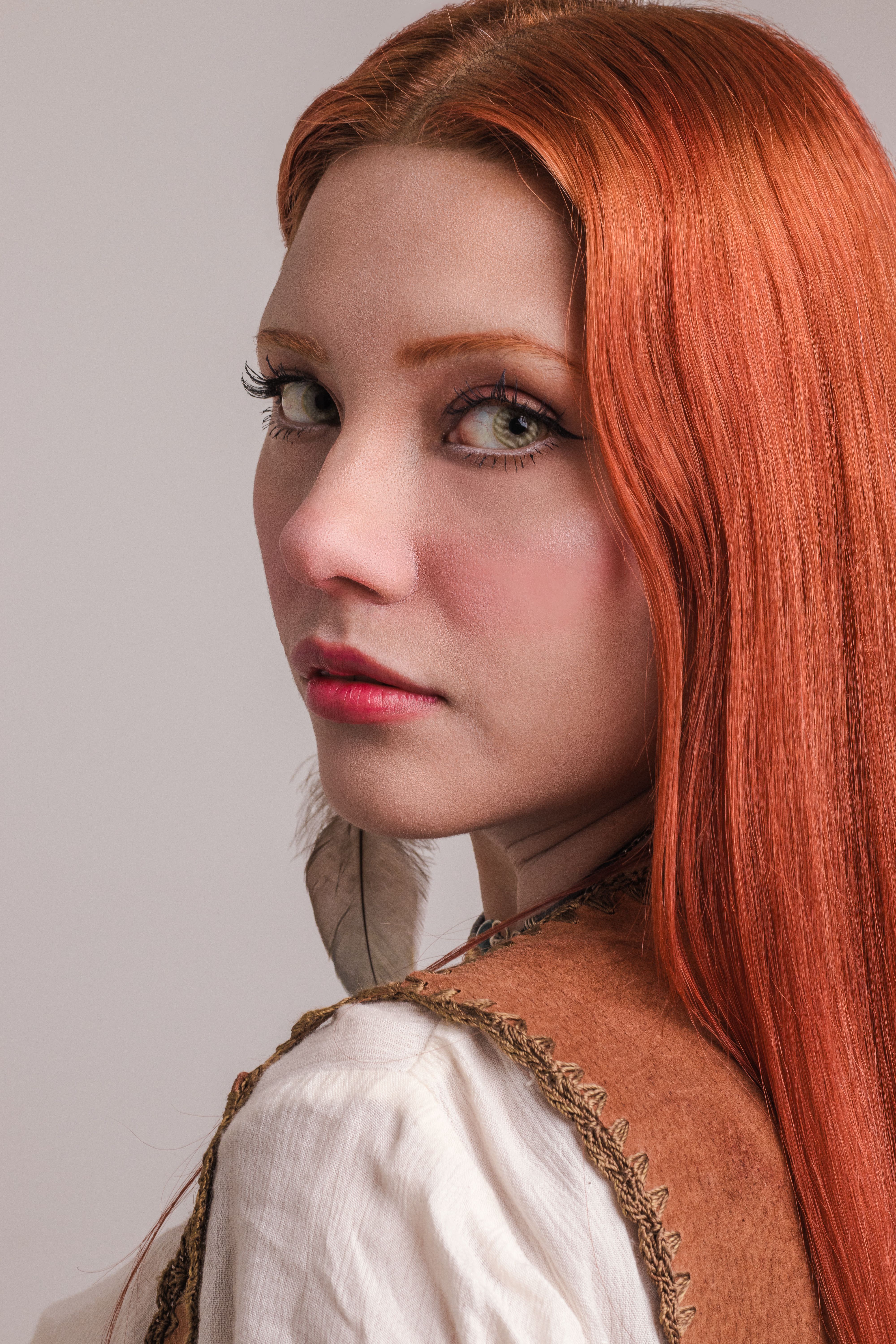 Portrait of a woman with striking red hair in soft light, showcasing elegance and beauty.