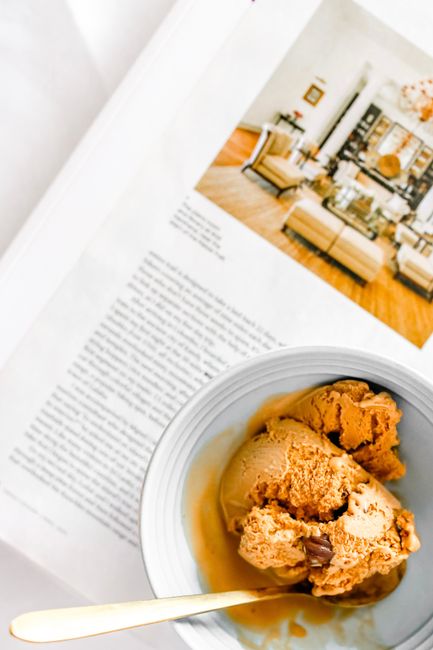 Creamy coffee ice cream in a bowl with a stylish magazine backdrop for a relaxed indoor vibe.
