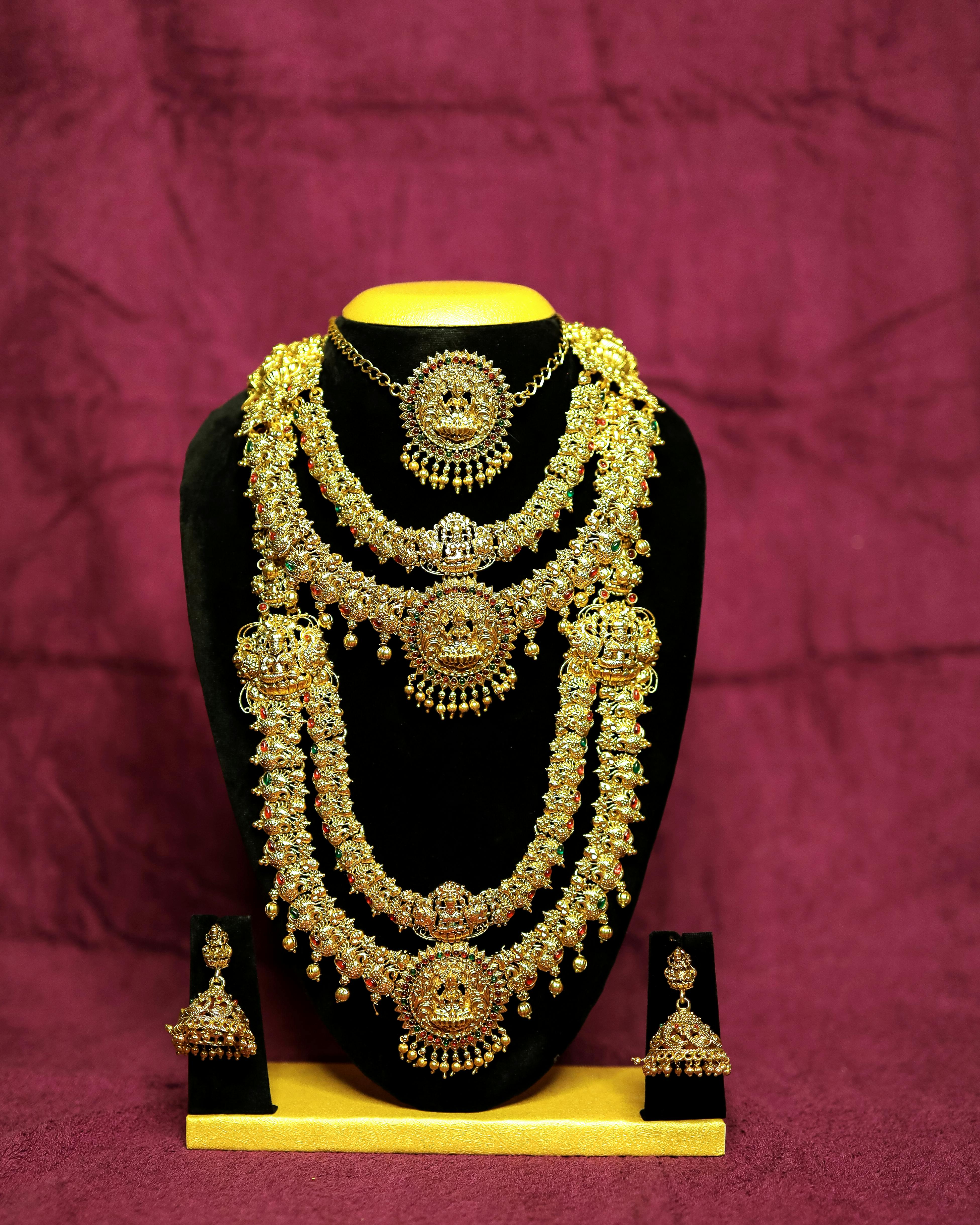 Elegant gold jewelry set including necklace and earrings on display stand, perfect for weddings.