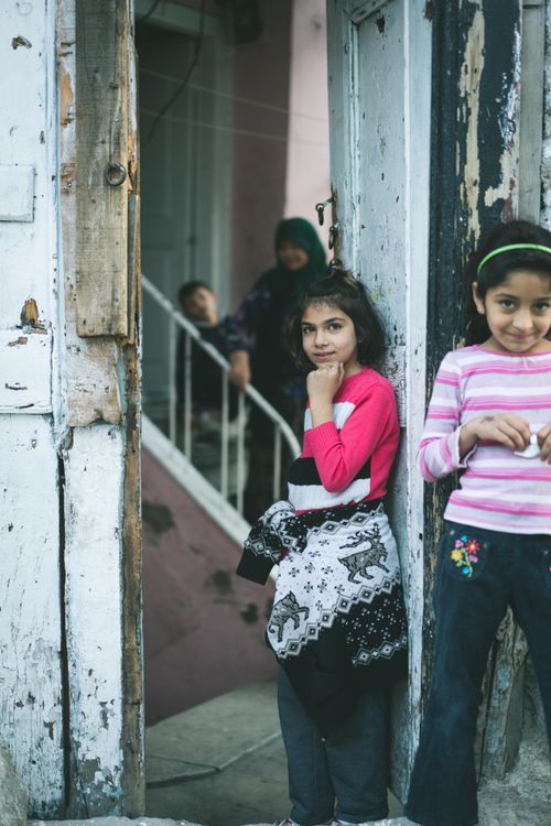 Free Two young girls smiling in a rustic doorway with family in background. Stock Photo