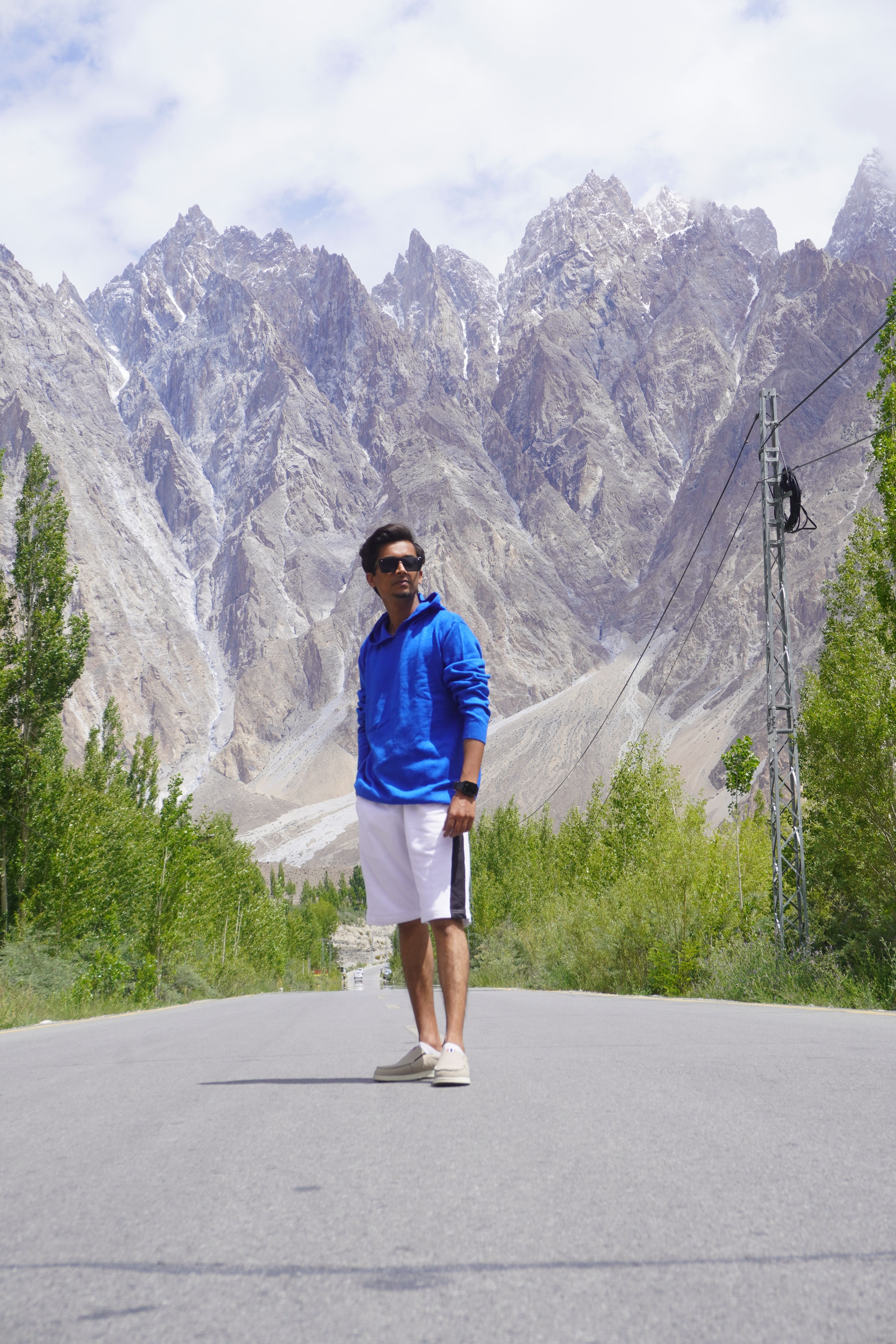 Man stands confidently on a scenic road with stunning mountains in the backdrop, Sindh, Pakistan.