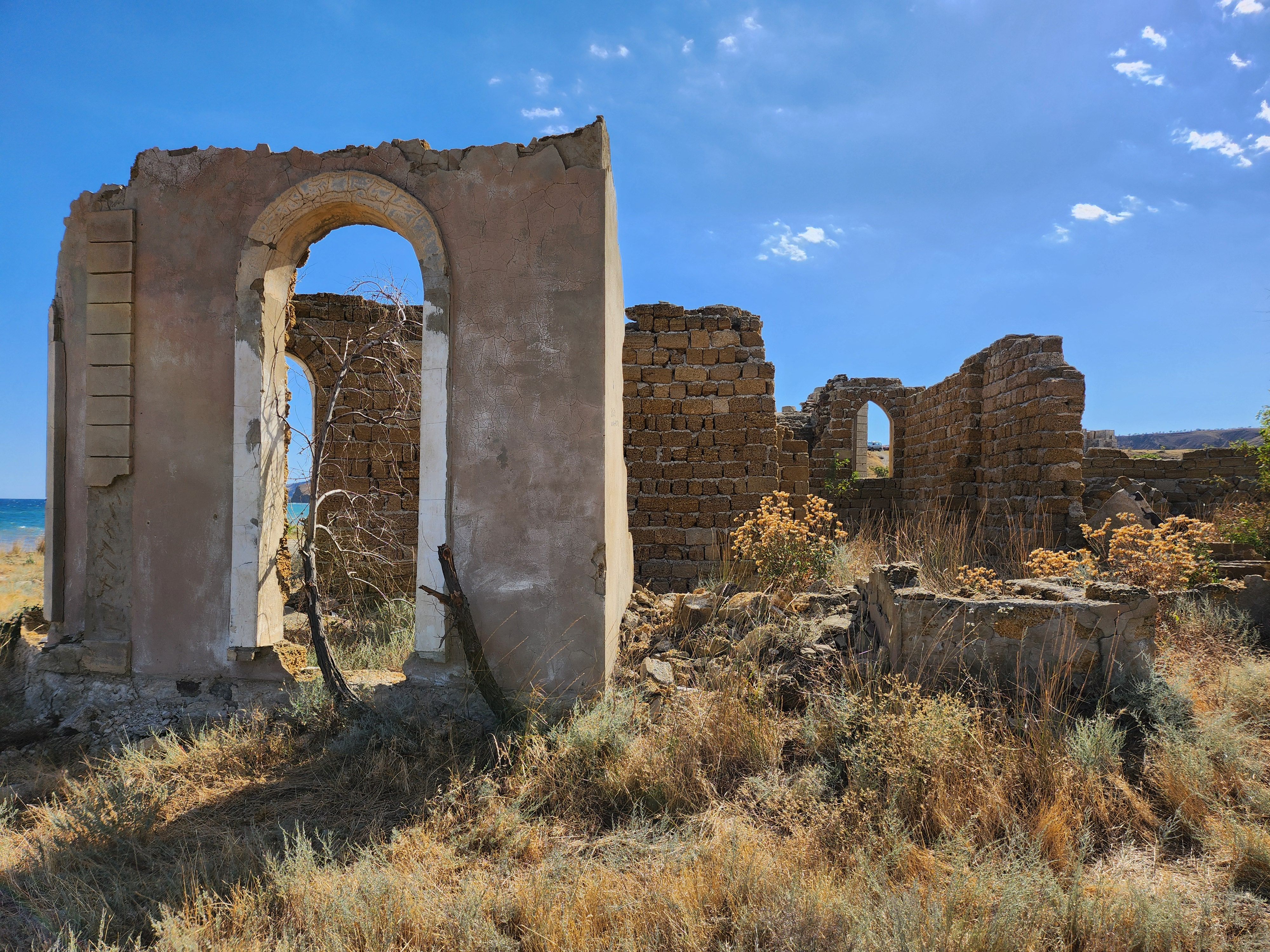 Ruines antiques envahies par la végétation sur fond de mer