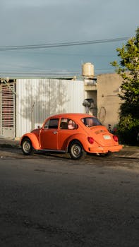 A vintage orange Beetle parked on a city street, capturing an urban vibe in late afternoon light.
