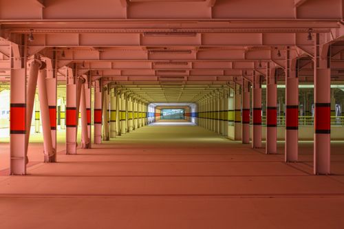 Free View of a symmetrical, empty urban tunnel featuring vibrant colors and structural columns. Stock Photo