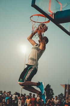 黄昏时分，运动员在室外篮球场上进行强力扣篮