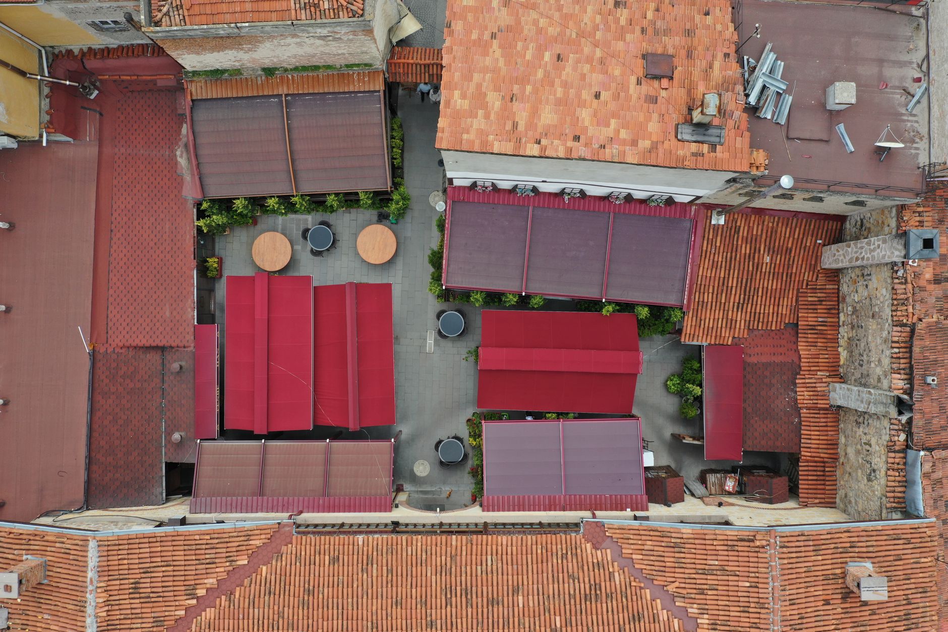 Drone shot of a courtyard in Kastamonu, Turkey with red sunshades and tables.