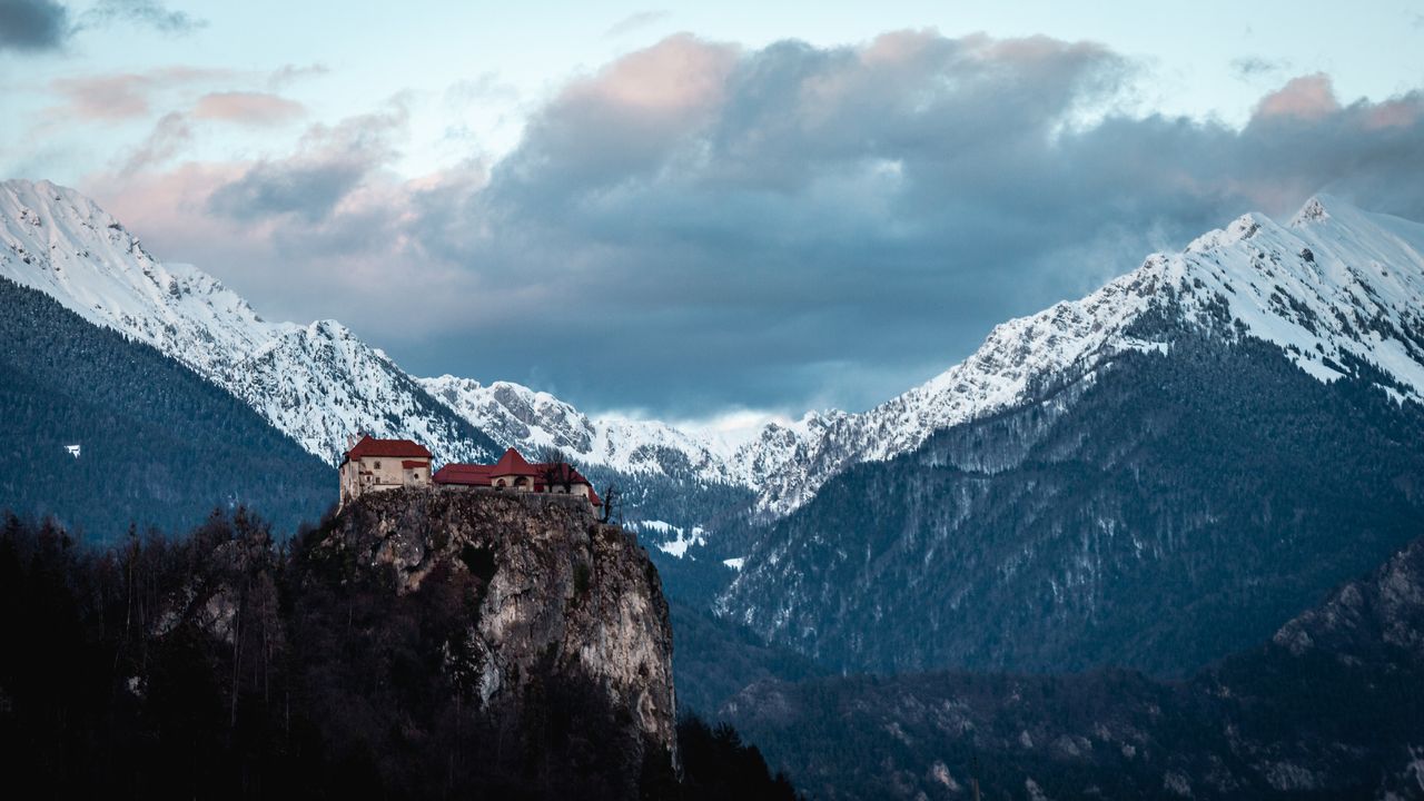 an awe inspiring view of a castle perched on a snowy cliff surrounded