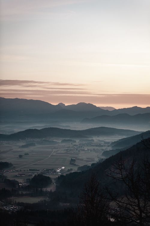 Free A breathtaking view of mountains and valleys at dawn with mist creating a serene atmosphere. Stock Photo