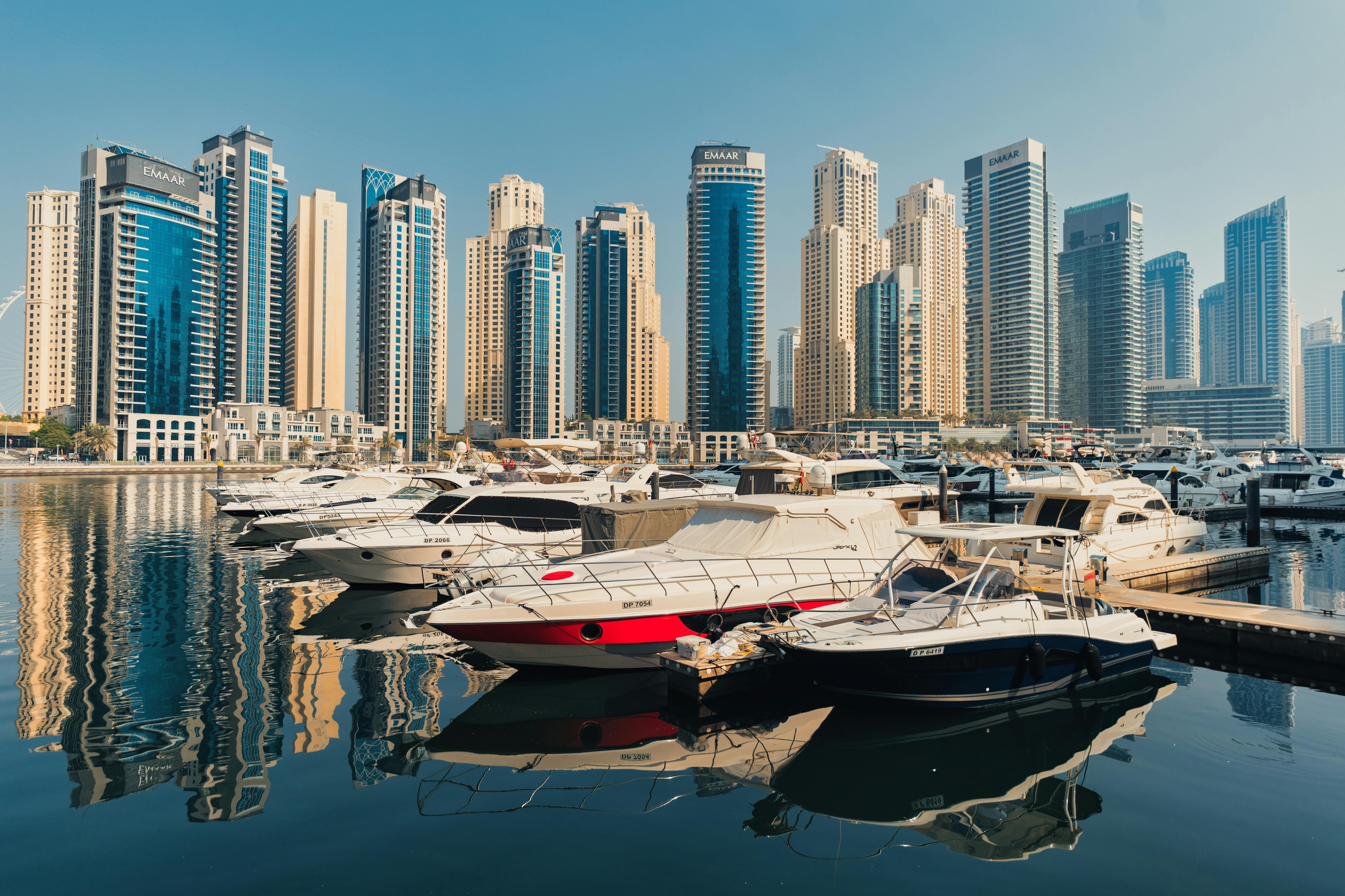 Scenic view of Dubai Marina's modern architecture and luxury yachts under blue sky.