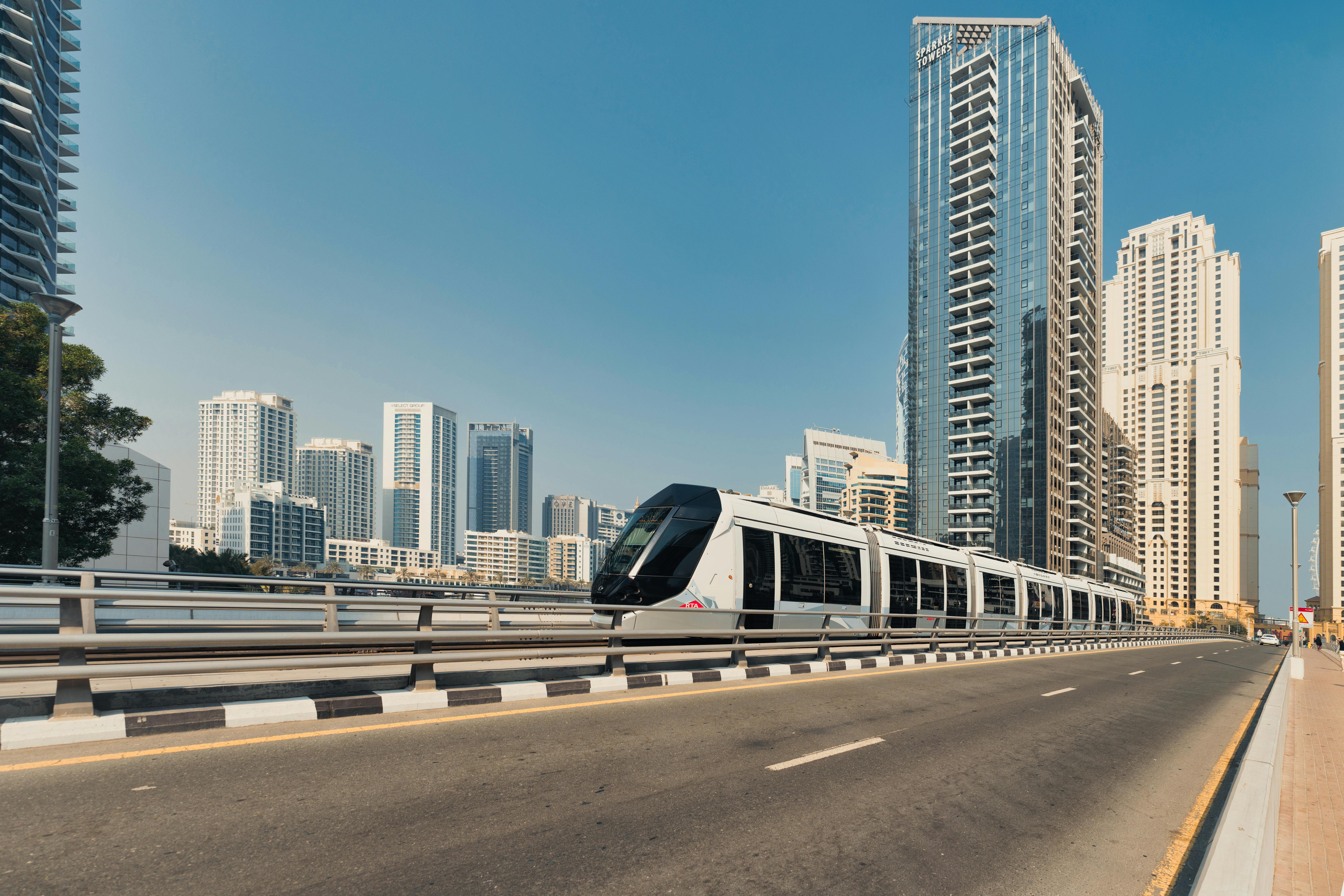 A sleek tram travels through a bustling Dubai cityscape showcasing towering skyscrapers.