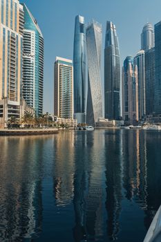 Stunning view of modern skyscrapers reflecting in the waters of Dubai Marina, showcasing urban architecture.