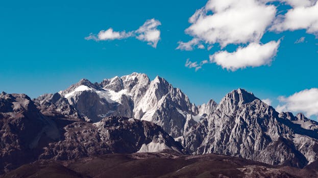 A breathtaking view of a rugged, snow-capped mountain range under a clear blue sky.