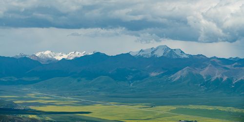 Free Scenic view of snow-capped mountains with vast valleys under dramatic clouds. Stock Photo