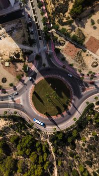 High-angle aerial view of a busy urban roundabout with vehicles and green spaces.