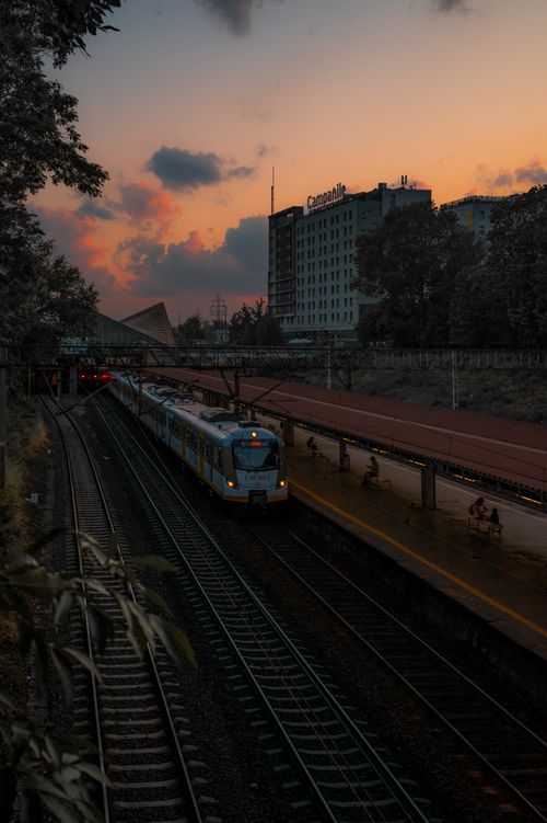 Free A train approaches Warsaw station under a colorful sunset, capturing urban travel ambiance. Stock Photo