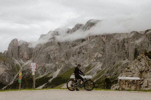 Free Cyclist reading map amidst misty mountains, a perfect nature adventure scene. Stock Photo