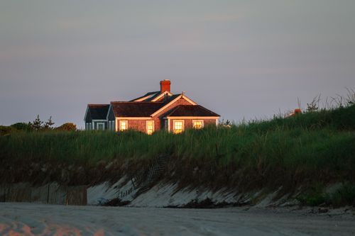 Free Charming coastal cottage on Nantucket beach at sunset, capturing serene summer vibes. Stock Photo